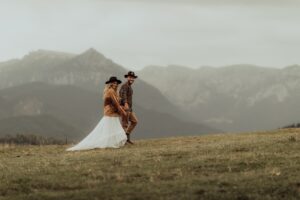 Beautiful stylish couple walks holding hands in a Carpathian mountain landscape.